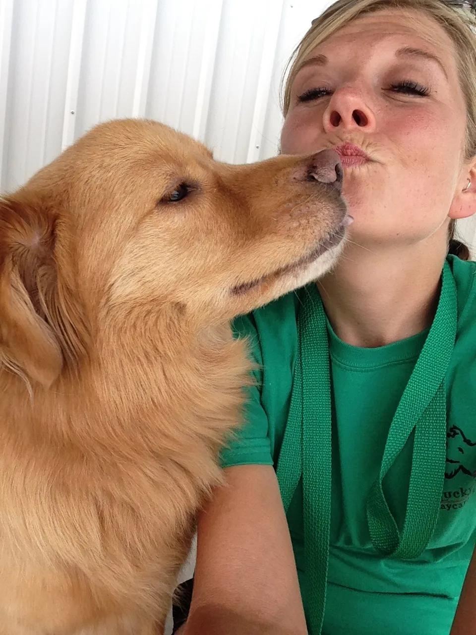 A golden retriever giving Shiloh Keuler a kiss at a dog rescue event